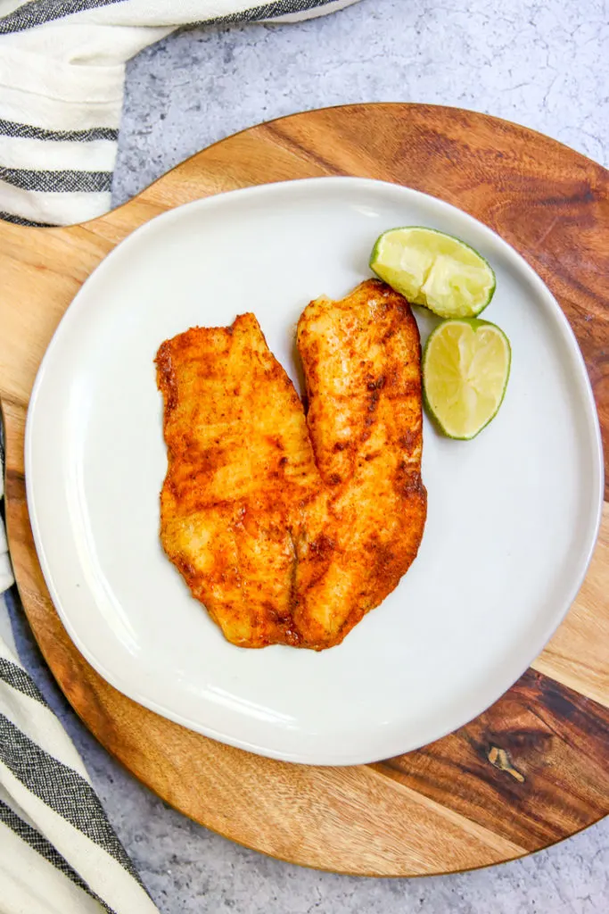 an overhead shot of chili lime tilapia on a white plate on a serving platter