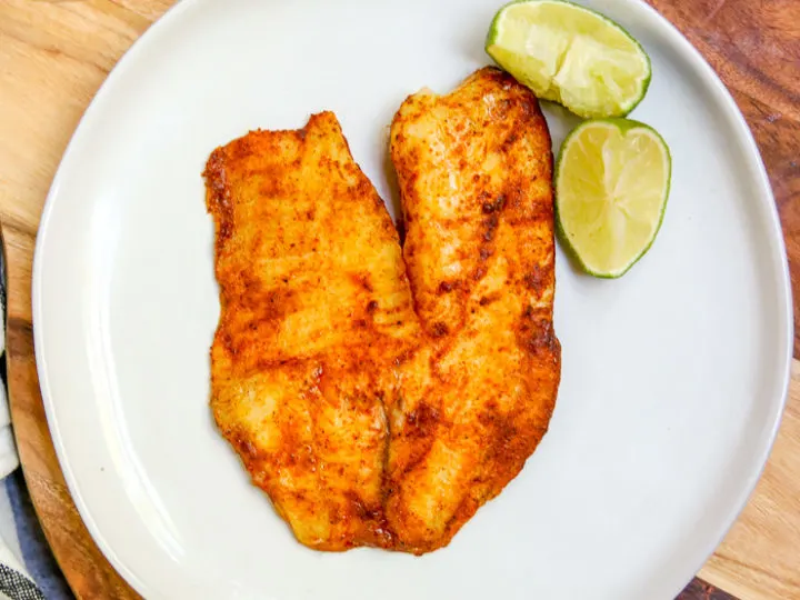 an overhead shot of chili lime tilapia on a white plate on a serving platter