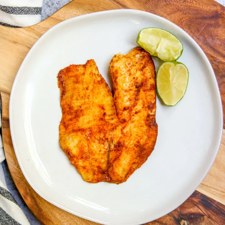 an overhead shot of chili lime tilapia on a white plate on a serving platter