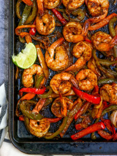 a close up of the cooked shrimp, peppers and onions on a cookie sheet