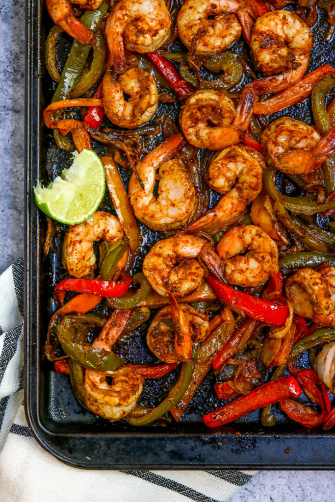 a close up of the cooked shrimp, peppers and onions on a cookie sheet