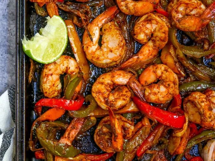 a close up of the cooked shrimp, peppers and onions on a cookie sheet