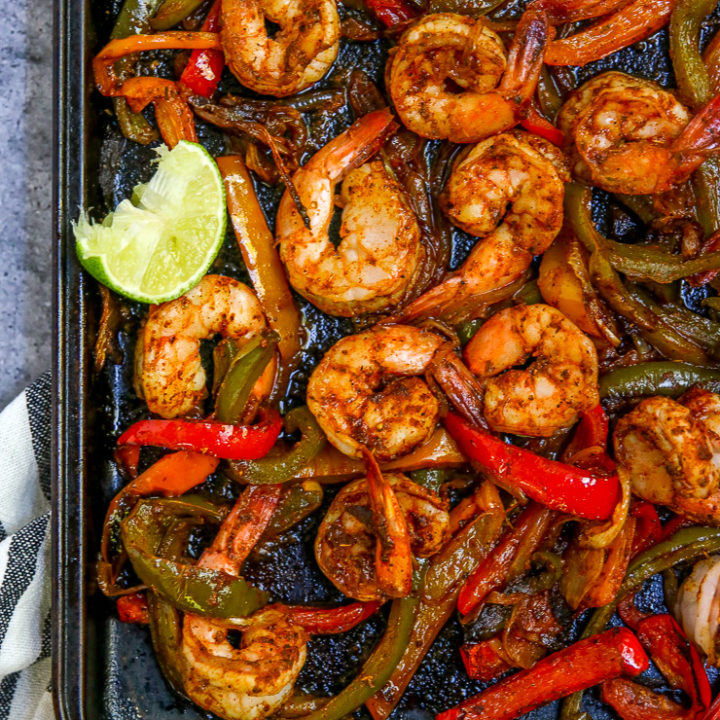 a close up of the cooked shrimp, peppers and onions on a cookie sheet