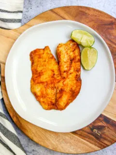 an overhead shot of chili lime tilapia on a white plate on a serving platter