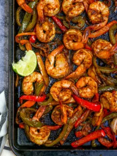 a close up of the cooked shrimp, peppers and onions on a cookie sheet