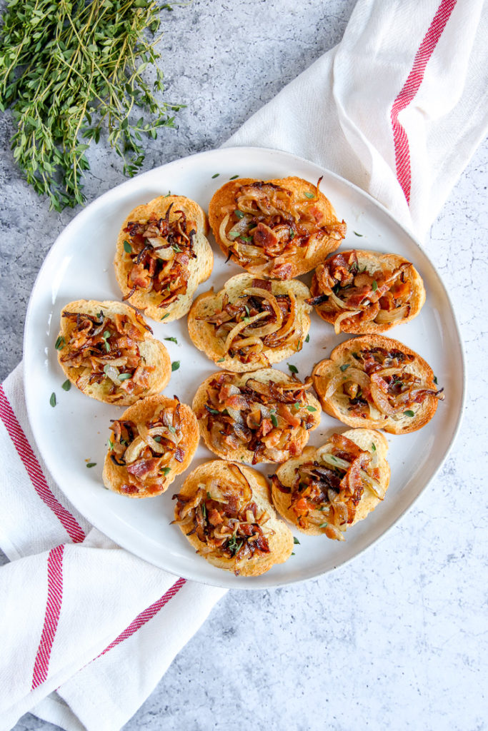 a plate of bacon caramelized onion crostini