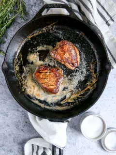 two pieces of filet mignon in a cast iron skillet