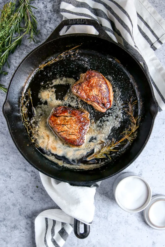 two pieces of filet mignon in a cast iron skillet