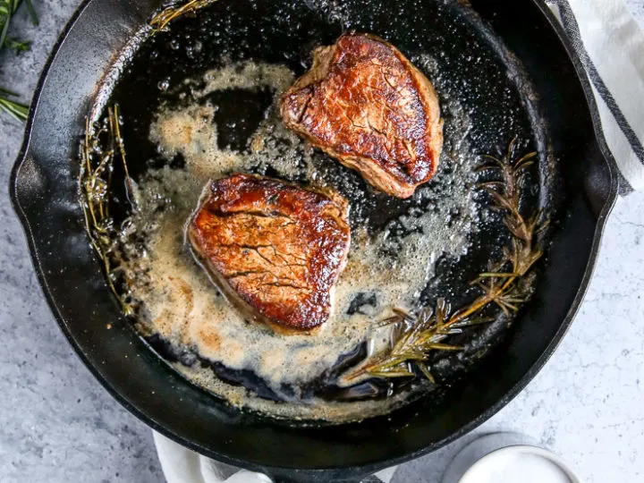 two pieces of filet mignon in a cast iron skillet