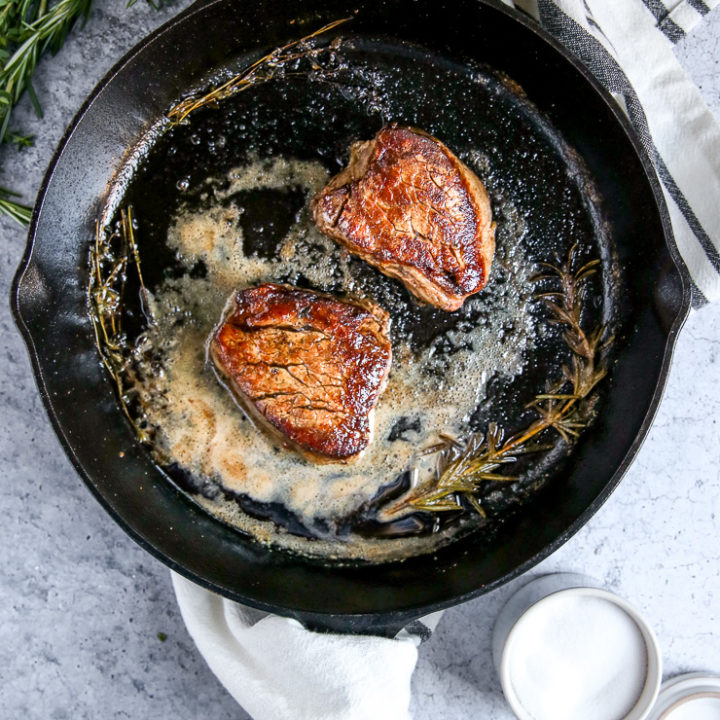 two pieces of filet mignon in a cast iron skillet