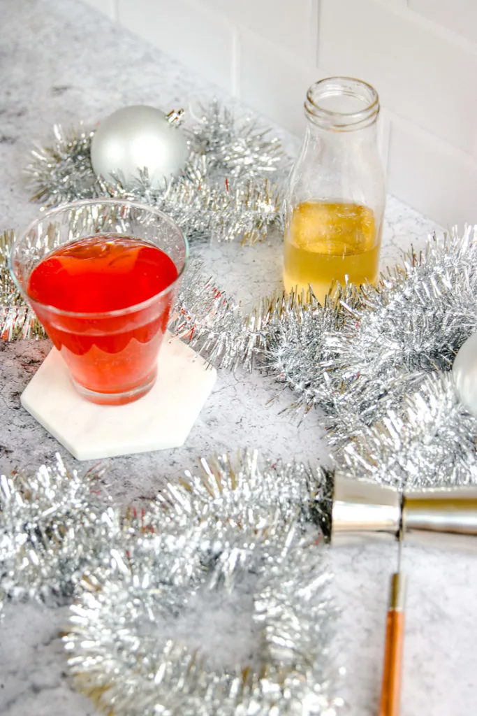 a jigger on a copper handle, a glass bottle of ginger ale, and a cranberry ginger ale punch