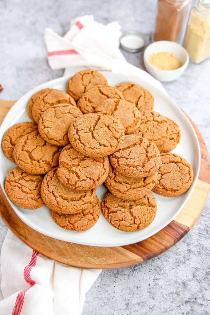 a pile of ginger snaps with jars of spices in the background