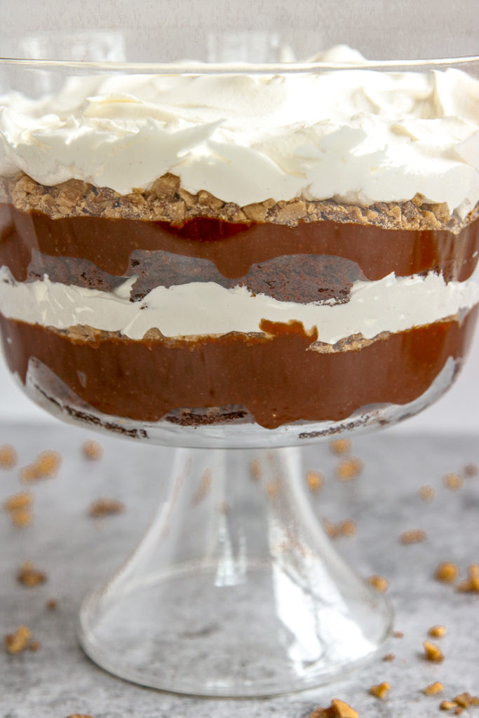 layers of brownie, pudding, heath crumbles and cool whip in a glass serving container