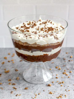 a heath bar trifle in front of subway tile on a gray table with heath bars crumbled