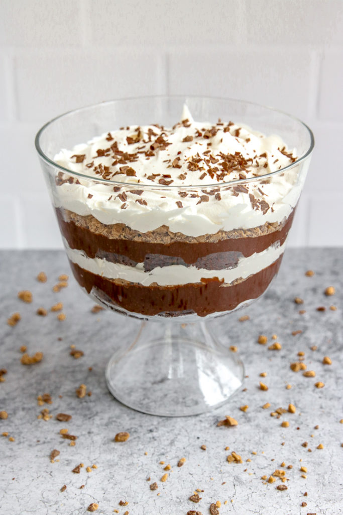 a heath bar trifle in front of subway tile on a gray table with heath bars crumbled