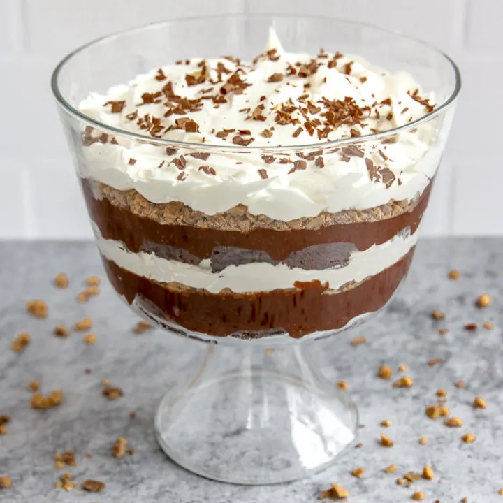 a heath bar trifle in front of subway tile on a gray table with heath bars crumbled