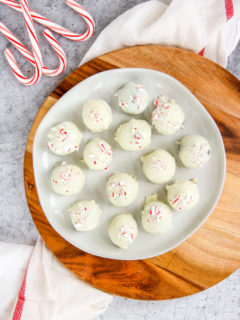 a plate of peppermint oreo truffles on a wooden platter next to candy canes