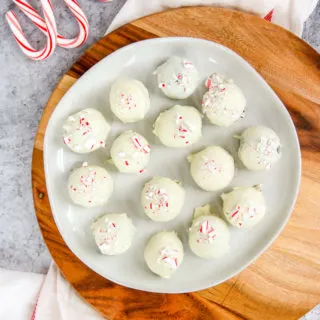a plate of peppermint oreo truffles on a wooden platter next to candy canes
