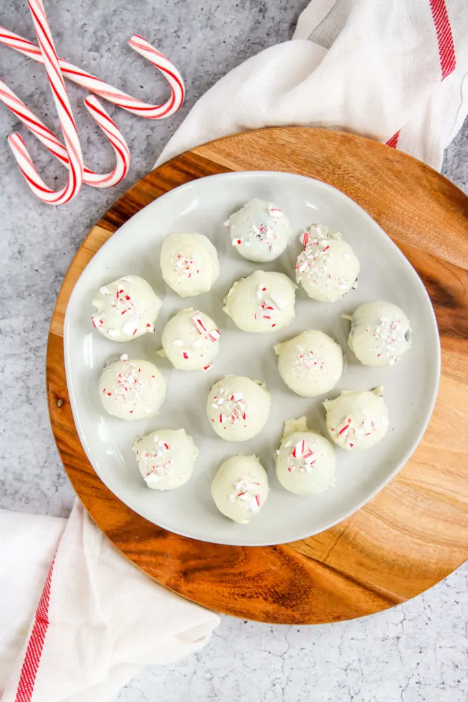 a plate of peppermint oreo truffles on a wooden platter next to candy canes