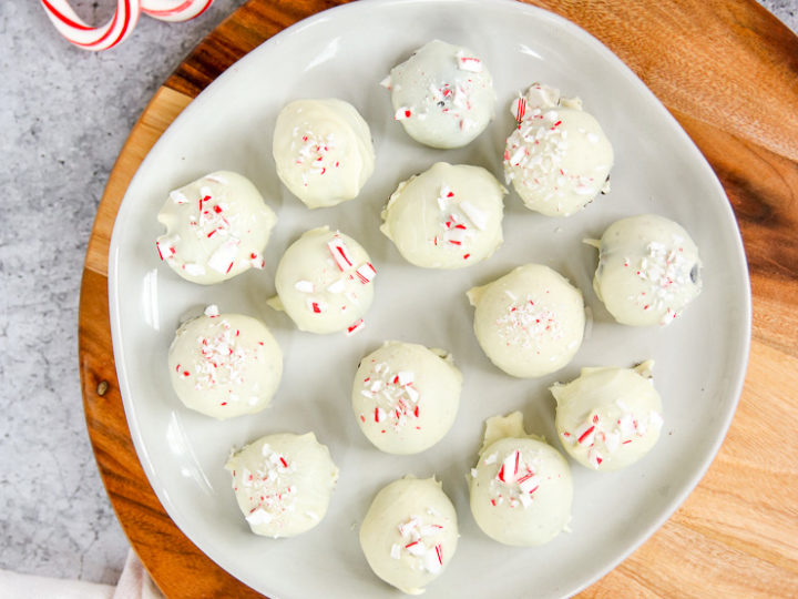 a plate of peppermint oreo truffles on a wooden platter next to candy canes