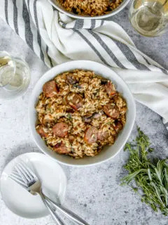 an overhead shot of two bowls of sausage mushroom risotto and two wine glasses