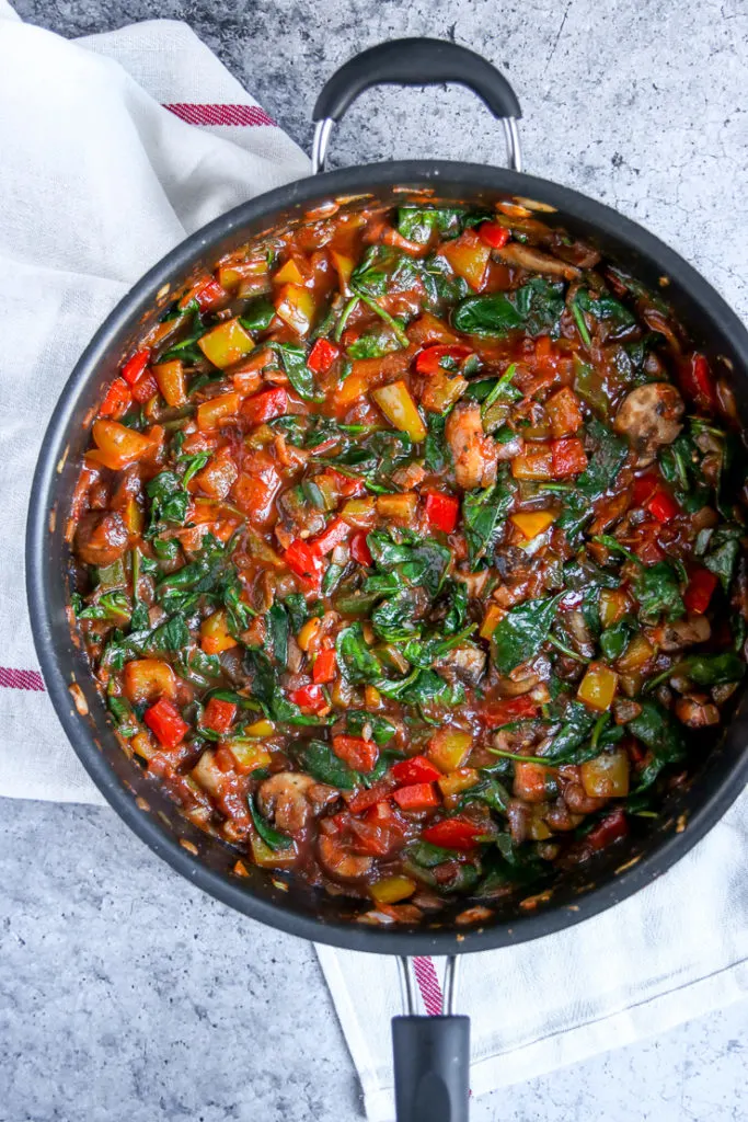 a skillet of sauteed spinach, mushrooms, and peppers