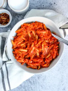 an overhead shot of penne alla vodka on a napkin with salt and red pepper flakes