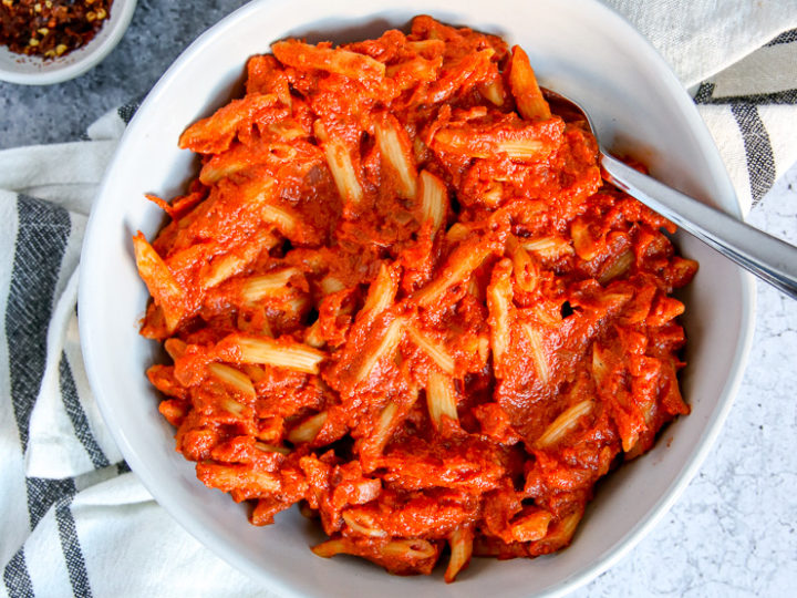 an overhead shot of penne alla vodka on a napkin with salt and red pepper flakes