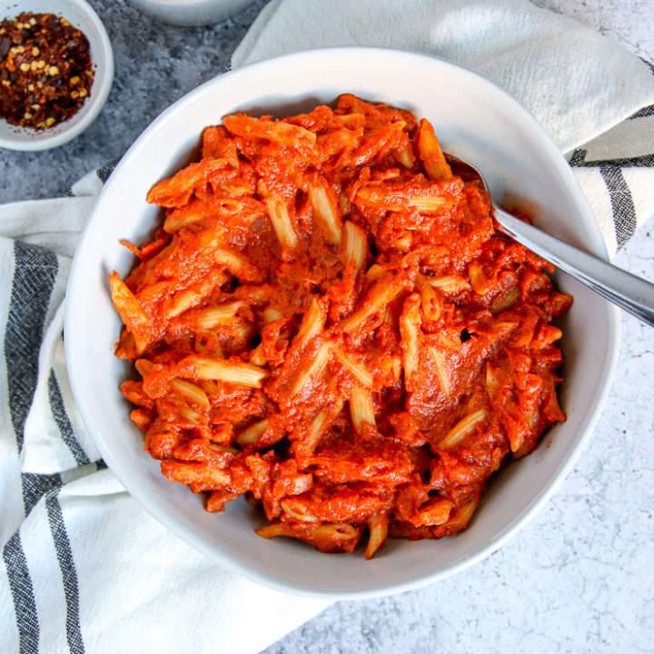 an overhead shot of penne alla vodka on a napkin with salt and red pepper flakes