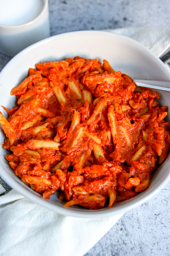 a close up of a white bowl and fork with penne alla vodka