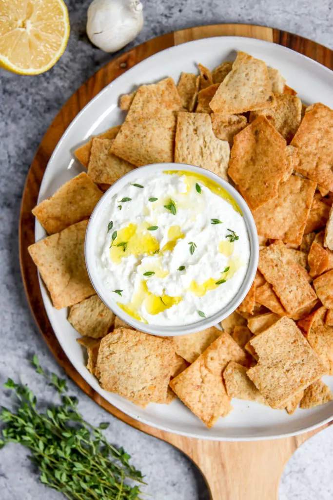 a bowl of whipped feta dip sitting on a plate with pita chips