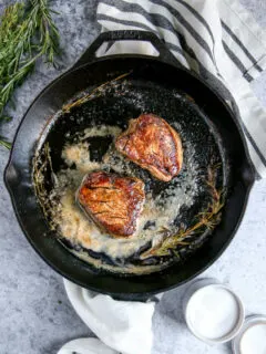two pieces of filet mignon in a cast iron skillet