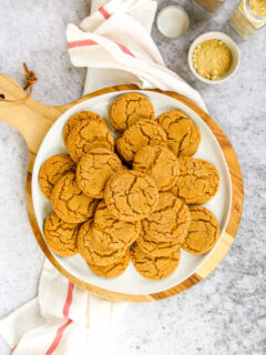 a white plate of ginger snaps on a wood platter next to a napkin