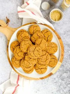 a white plate of ginger snaps on a wood platter next to a napkin