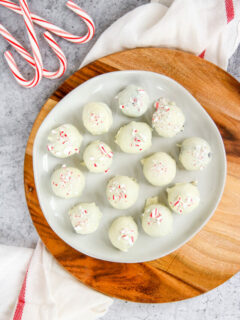 a plate of peppermint oreo truffles on a wooden platter next to candy canes