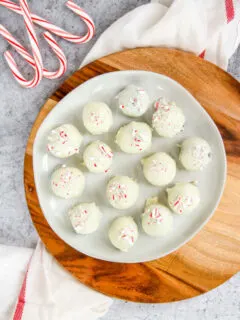 a plate of peppermint oreo truffles on a wooden platter next to candy canes