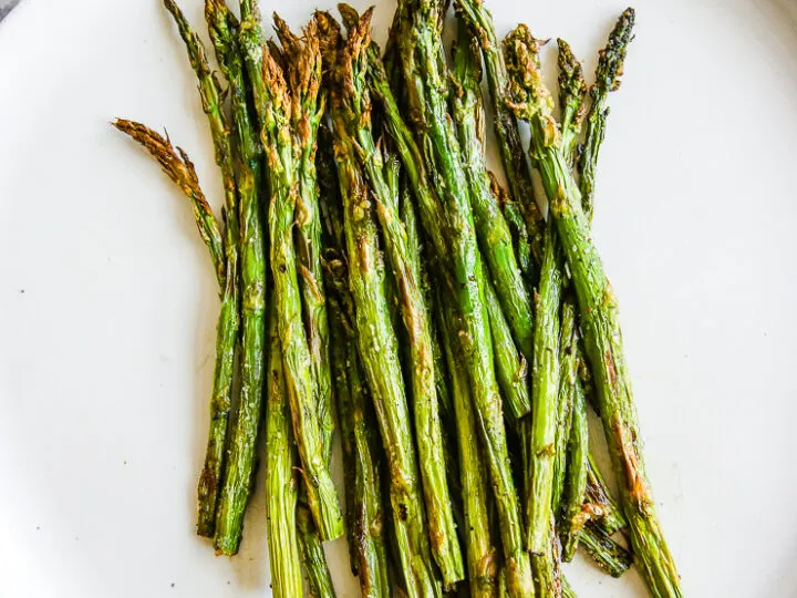 a white plate full of asparagus right from the air fryer