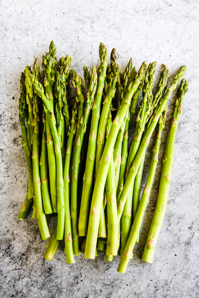 a bunch of asparagus on a grey background