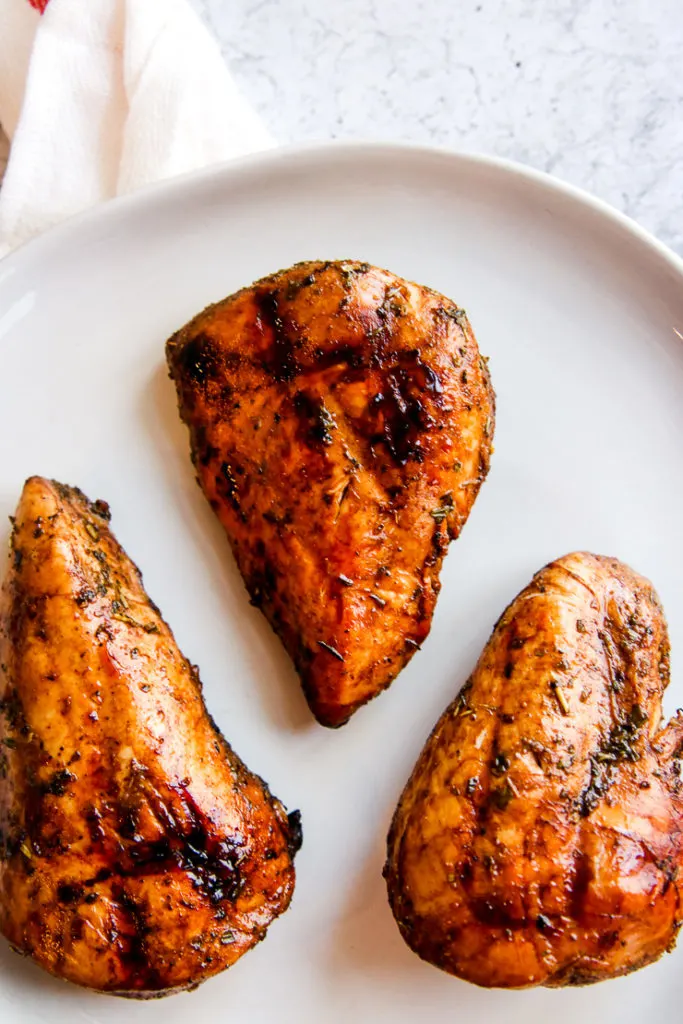 three balsamic grilled chicken breasts on a white plate