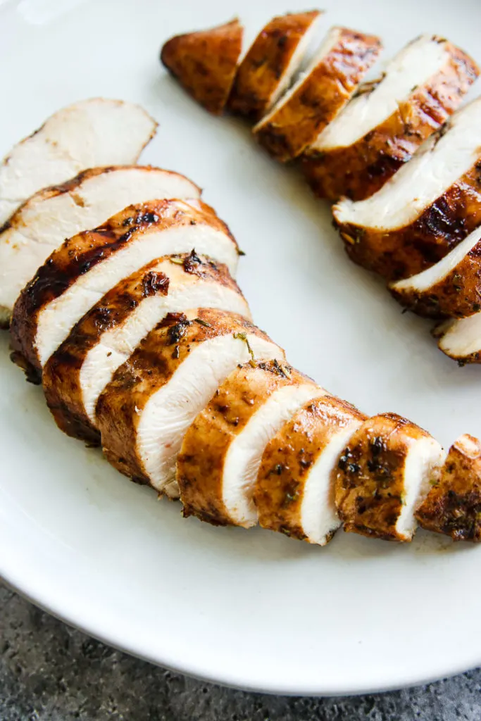 a close up of two sliced balsamic grilled chicken breasts on a white plate