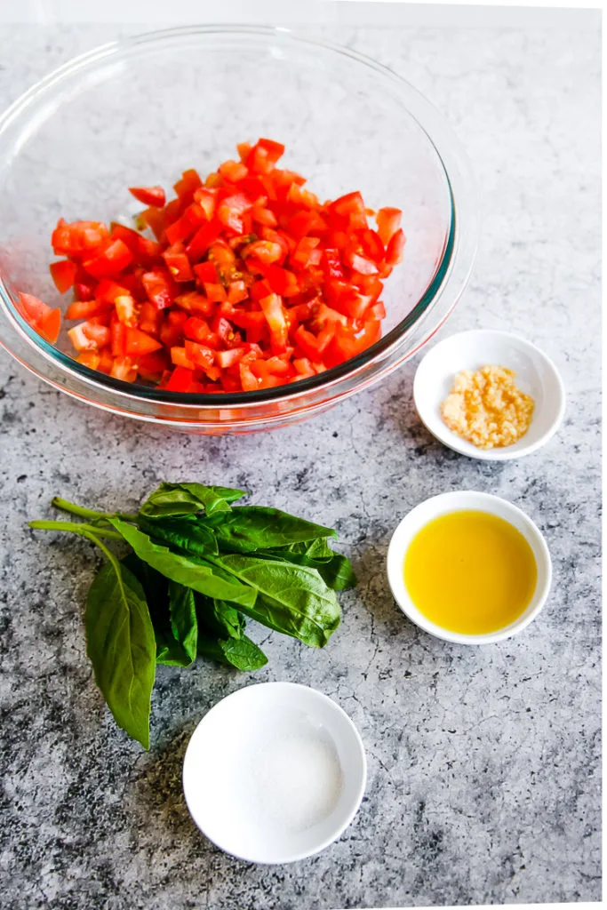 bowls of diced tomatoes, minced garlic, olive oil, salt, and a bunch of basil