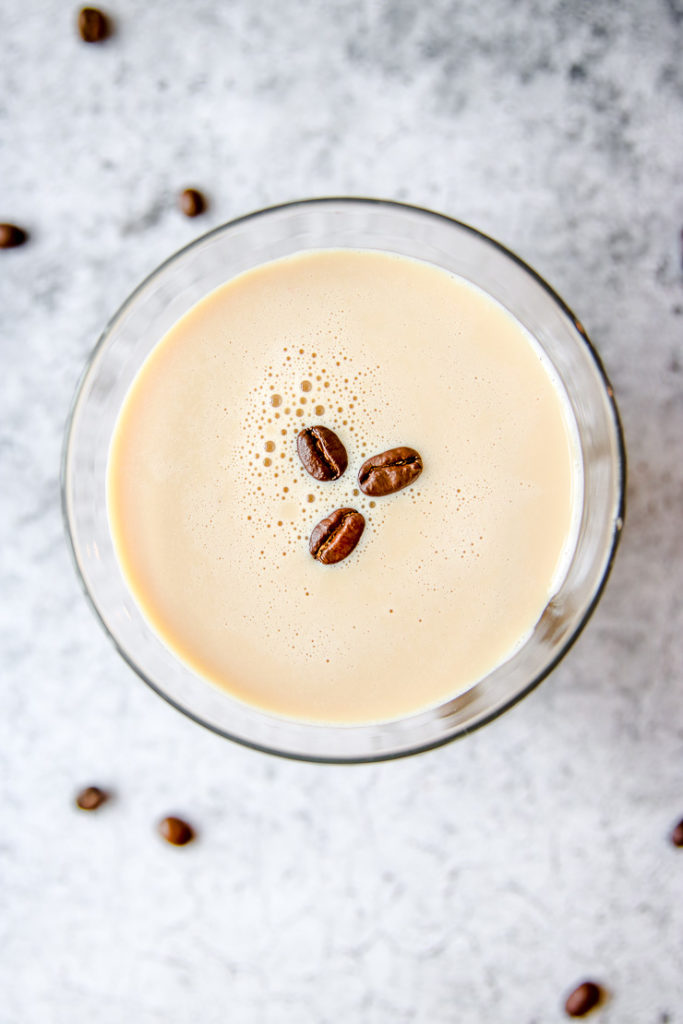 an overhead shot of a martini glass with three coffee beans floating on the espresso martini