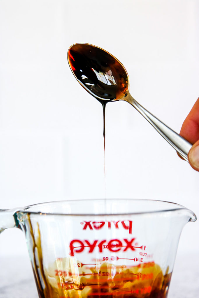 a spoon dipped in balsamic reduction over the pyrex