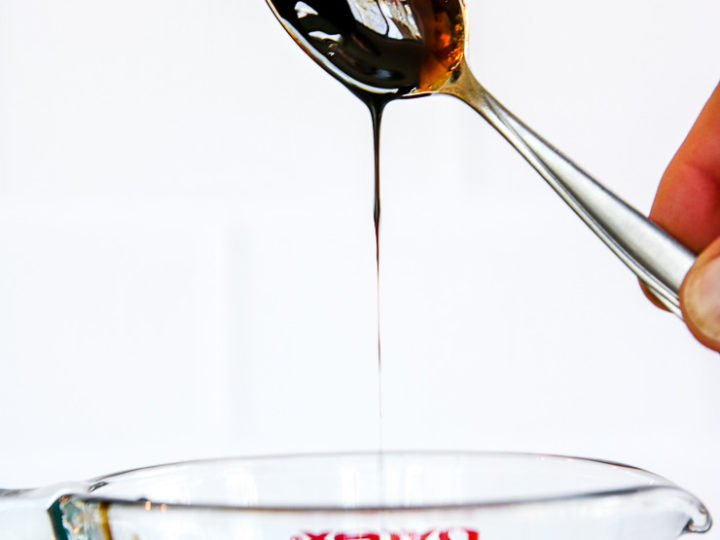 a spoon dipped in balsamic reduction over the pyrex