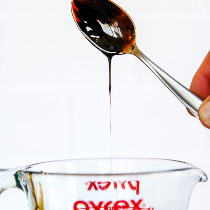 a spoon dipped in balsamic reduction over the pyrex