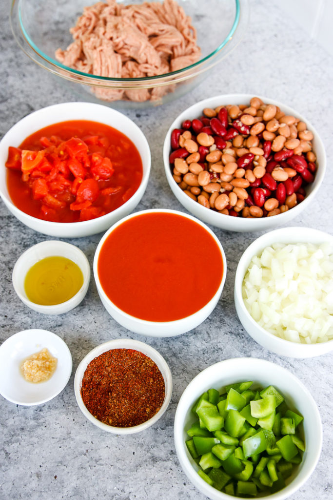 bowls of ground turkey, tomatoes, beans, diced onions, diced green peppers, and seasonings