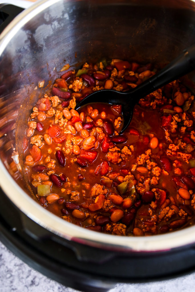 ground turkey chili in the instant pot being stirred