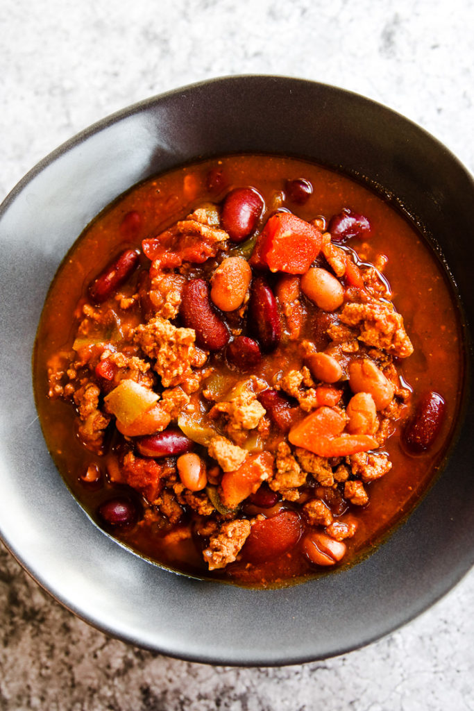 a grey bowl of instant pot ground turkey chili on a grey background