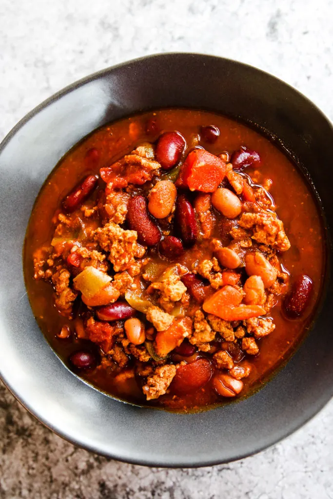 a grey bowl of instant pot ground turkey chili on a grey background