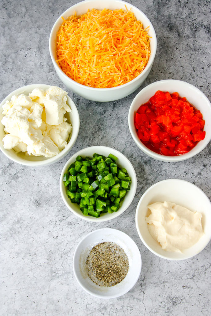 white bowls of shredded cheese, cream cheese, pimento cheese, diced jalapenos, mayo, and salt and pepper